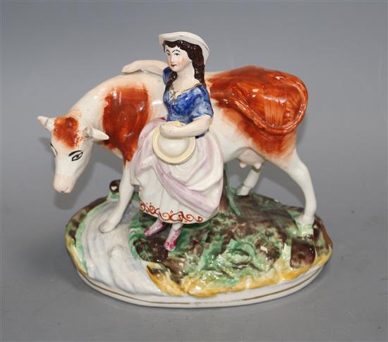 A Staffordshire pottery group of a milkmaid and cow, L. 21cm